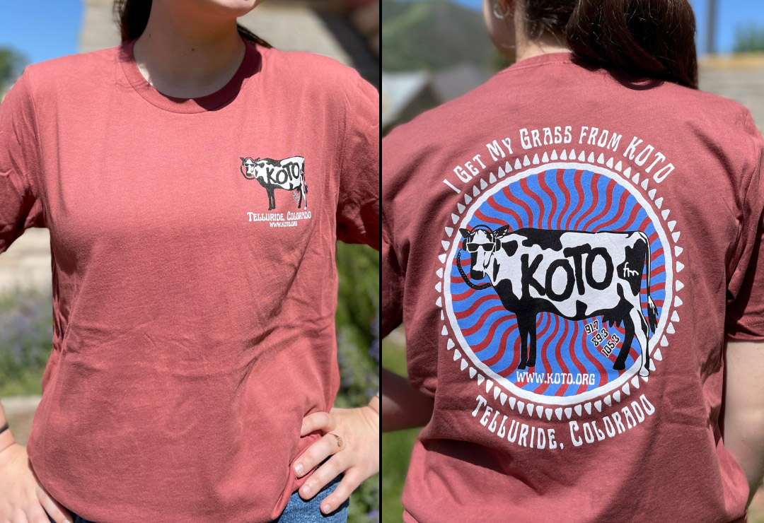 Two images of a person wearing a maroon T-shirt. The front features a logo with KOTO and Telluride, Colorado. The back displays a colorful design with a cow and text: I get my grass from KOTO, and Telluride, Colorado.