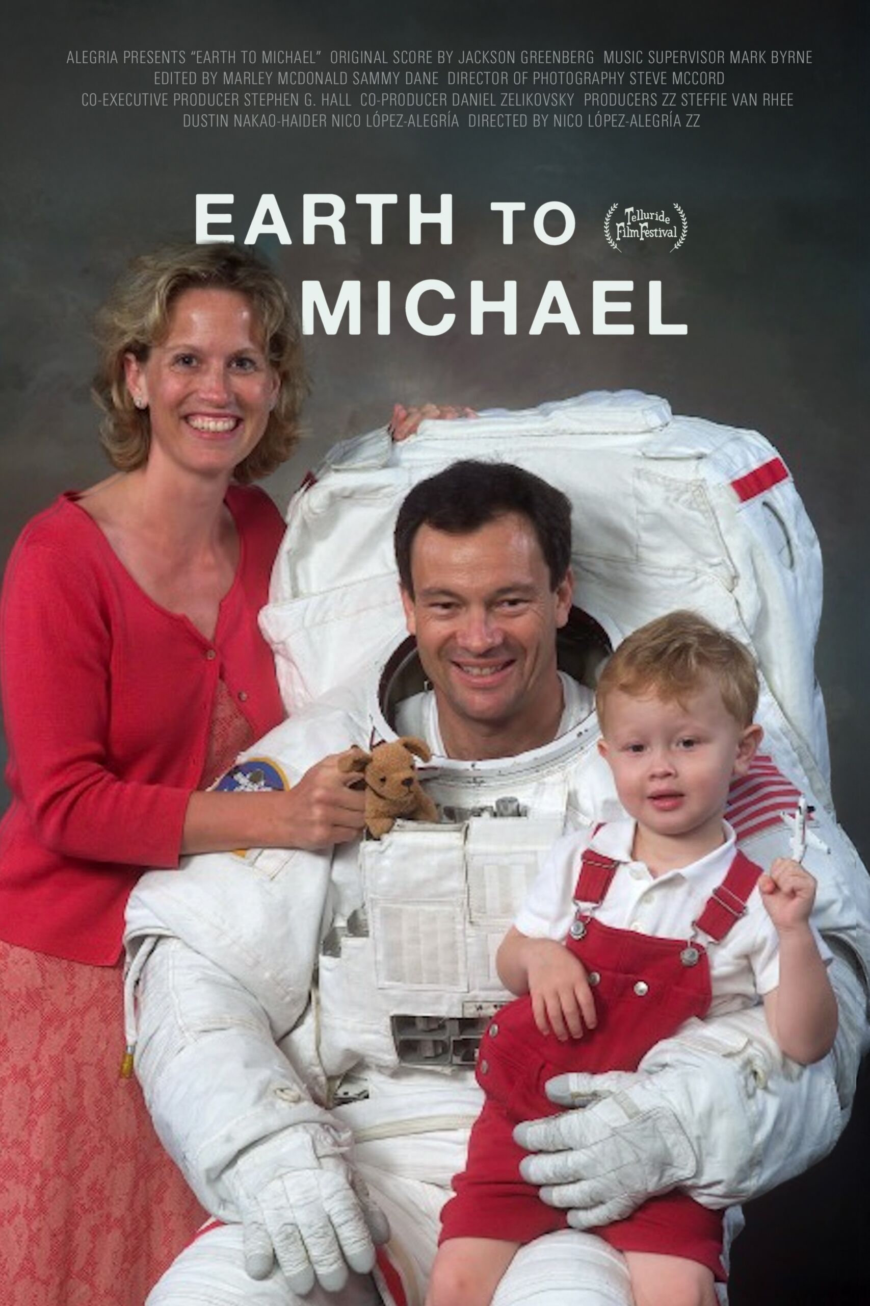 A smiling man in a spacesuit poses with a woman and a young boy in red overalls, evoking the spirit of the Film Series "Earth to Michael," all set against a gray studio backdrop.